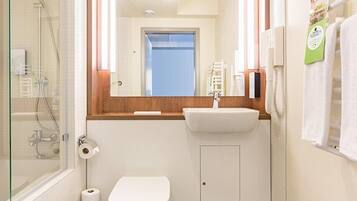 Un bagno con cabina doccia in vetro, lavandino, water e specchio.