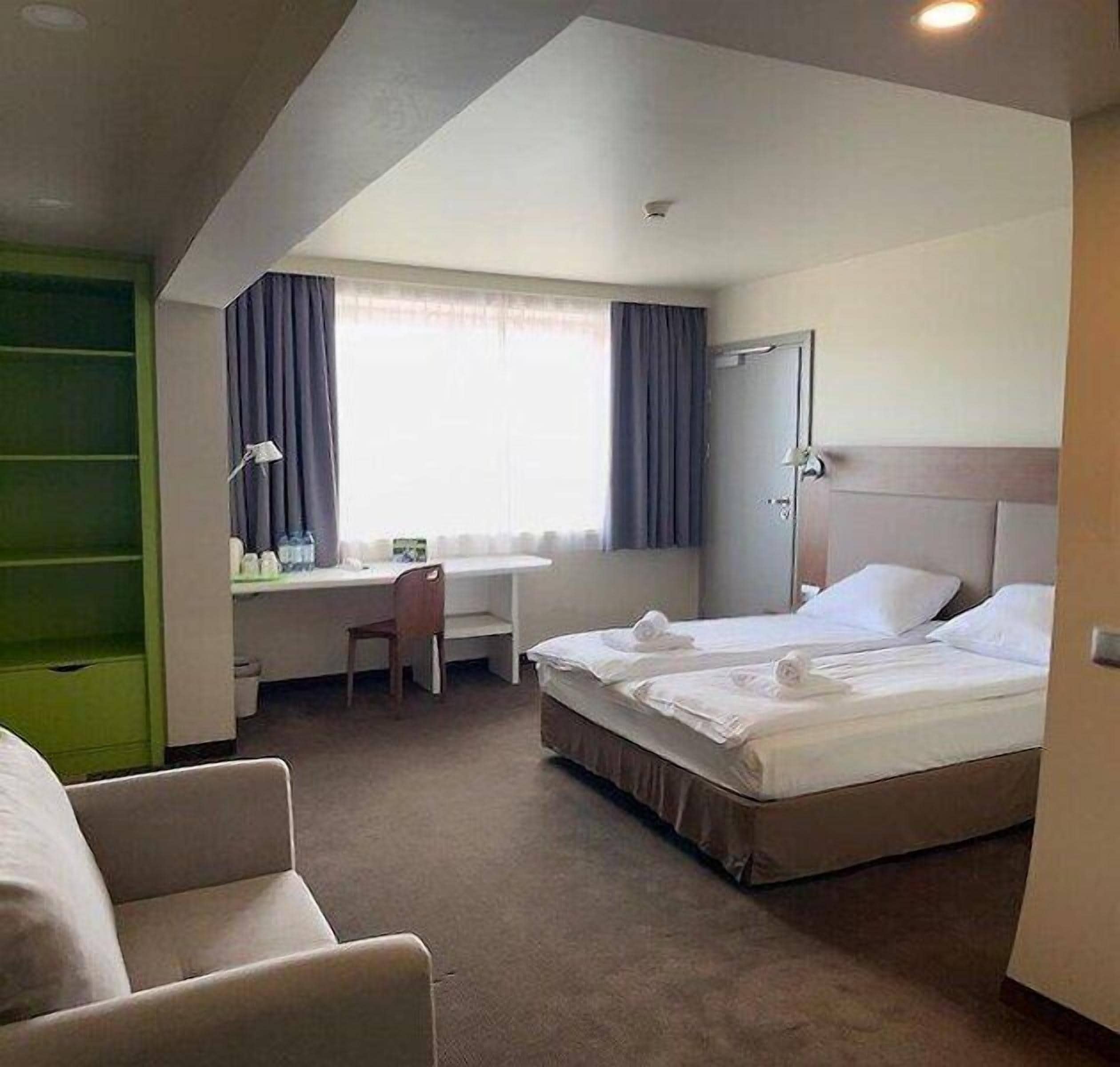 Een hotelkamer met een bed, een bureau, een stoel en een kledingkast.