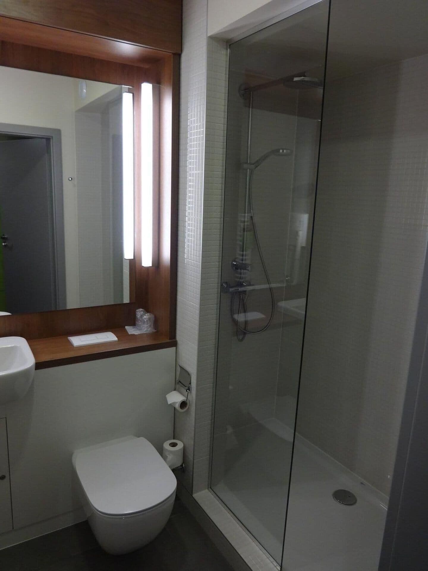 A bathroom with a toilet, sink, and glass-enclosed shower stall.
