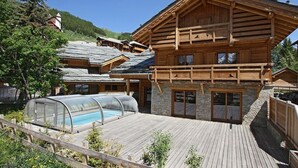 A wooden chalet with a swimming pool, stone walls, and a wooden deck. - Chalet, 50m from resort center, swimming pool, sauna, balcony, fireplace or stove, parking, tv (Les Deux Alpes)