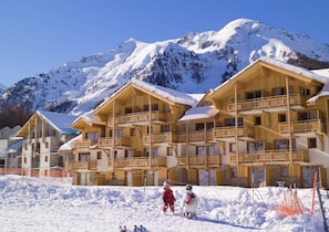 A wooden chalet-style hotel with multiple balconies, set against a snowy mountain backdrop. - Wifi, 50m from shops, view ski slopes, swimming pool, balcony, 28-29m², Les Orres (Les Orres)