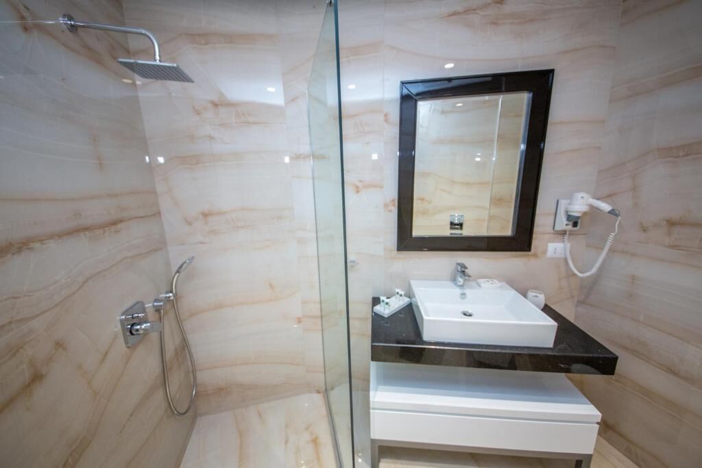A modern bathroom with a glass-enclosed shower, a white sink, and a mirror above it.