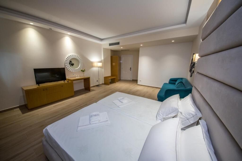 Ein Hotelzimmer mit Bett, Fernseher, Schreibtisch und einer kleinen Sitzecke.