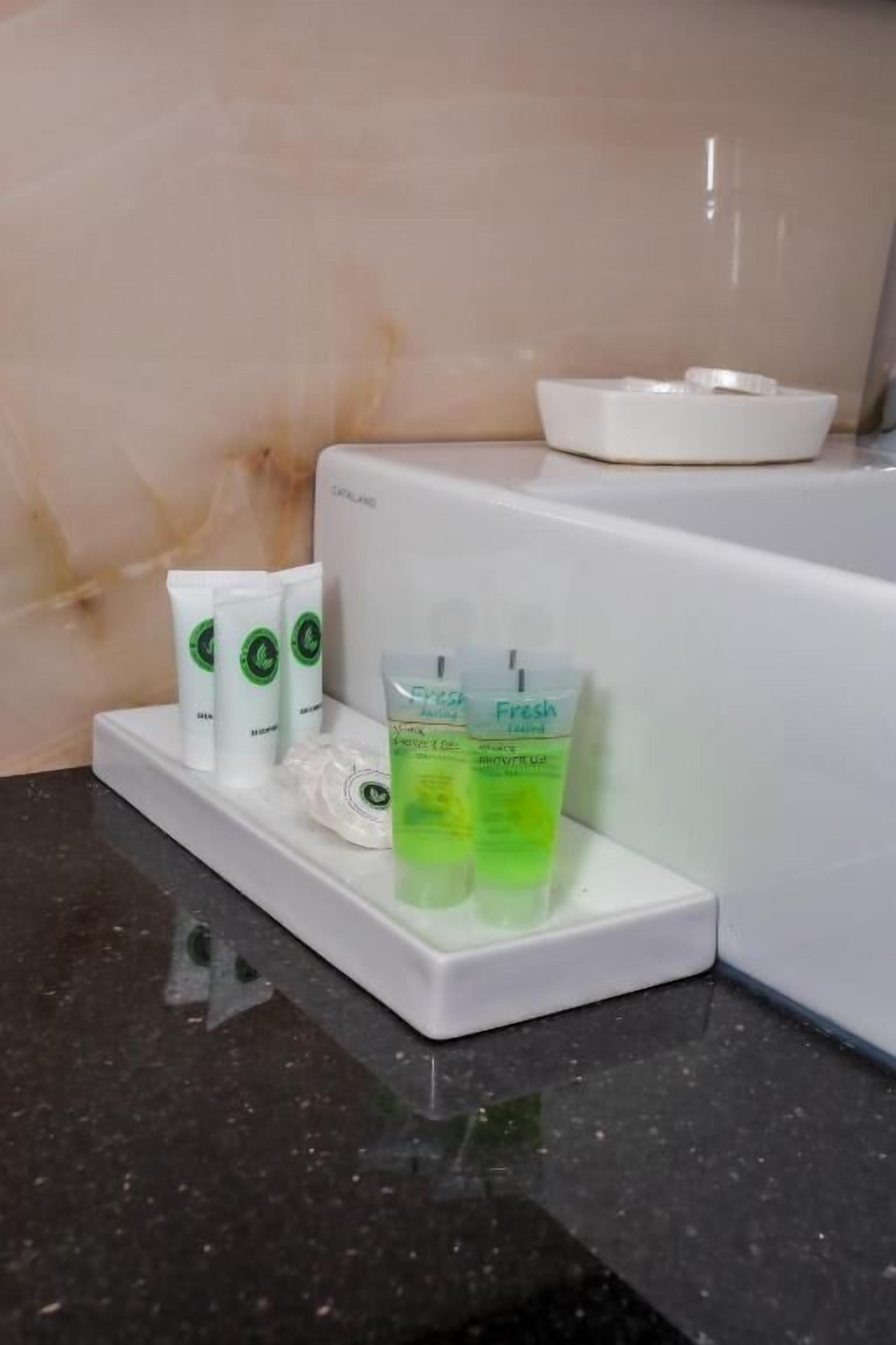 A bathroom counter with toiletries including a toothbrush, toothpaste, and a green bottle.
