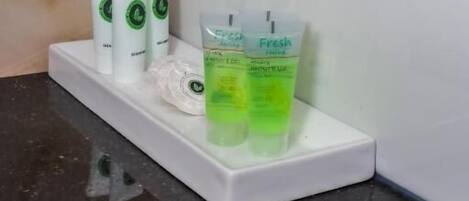A bathroom counter with toiletries including a toothbrush, toothpaste, and a green bottle.