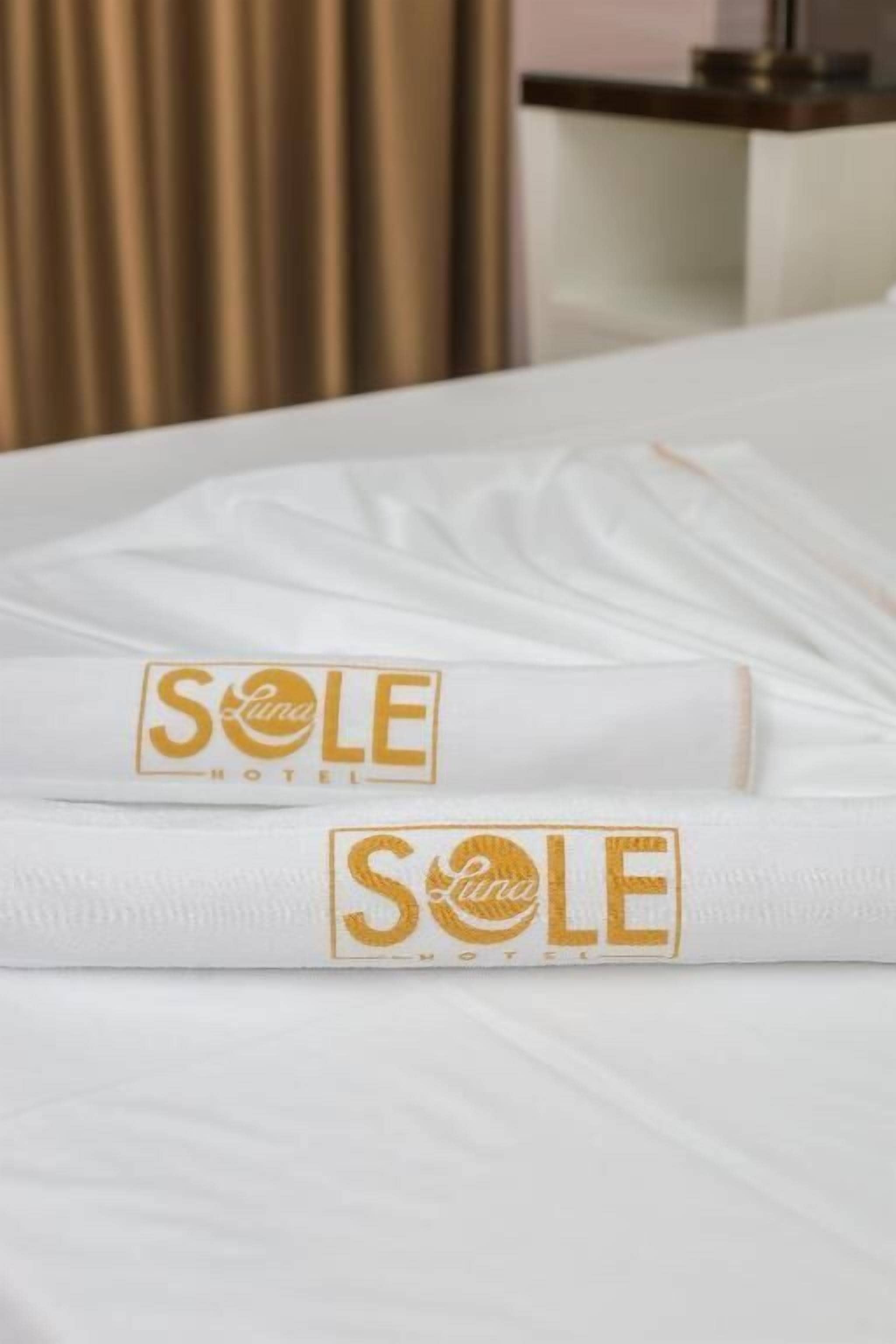 Biancheria da letto bianca e ordinata con il logo del SOLE HOTEL.