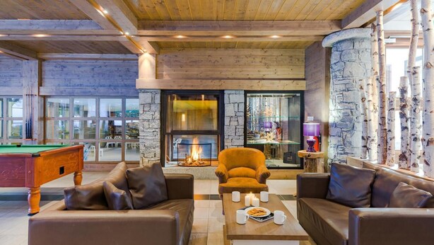 A cozy indoor setting with a fireplace, leather sofas, a pool table, and a view through large windows. - 300m from resort center, fitness, swimming pool, sauna, hammam, terrace, balcony, tv, ski locker (Les Gets)