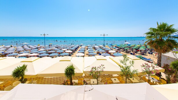 A beach with numerous umbrellas and sun loungers, a clear sky, and a calm sea. - Hotel Alion (Durrës)