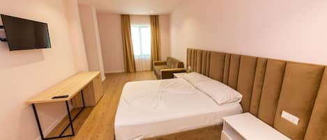 Une chambre d’hôtel moderne équipée d’un lit, d’un bureau, d’une chaise et d’un téléviseur fixé au mur.