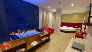 A modern hotel room with a large bed, a small seating area, a desk, and a large window. - Hotel Alion (Durrës)