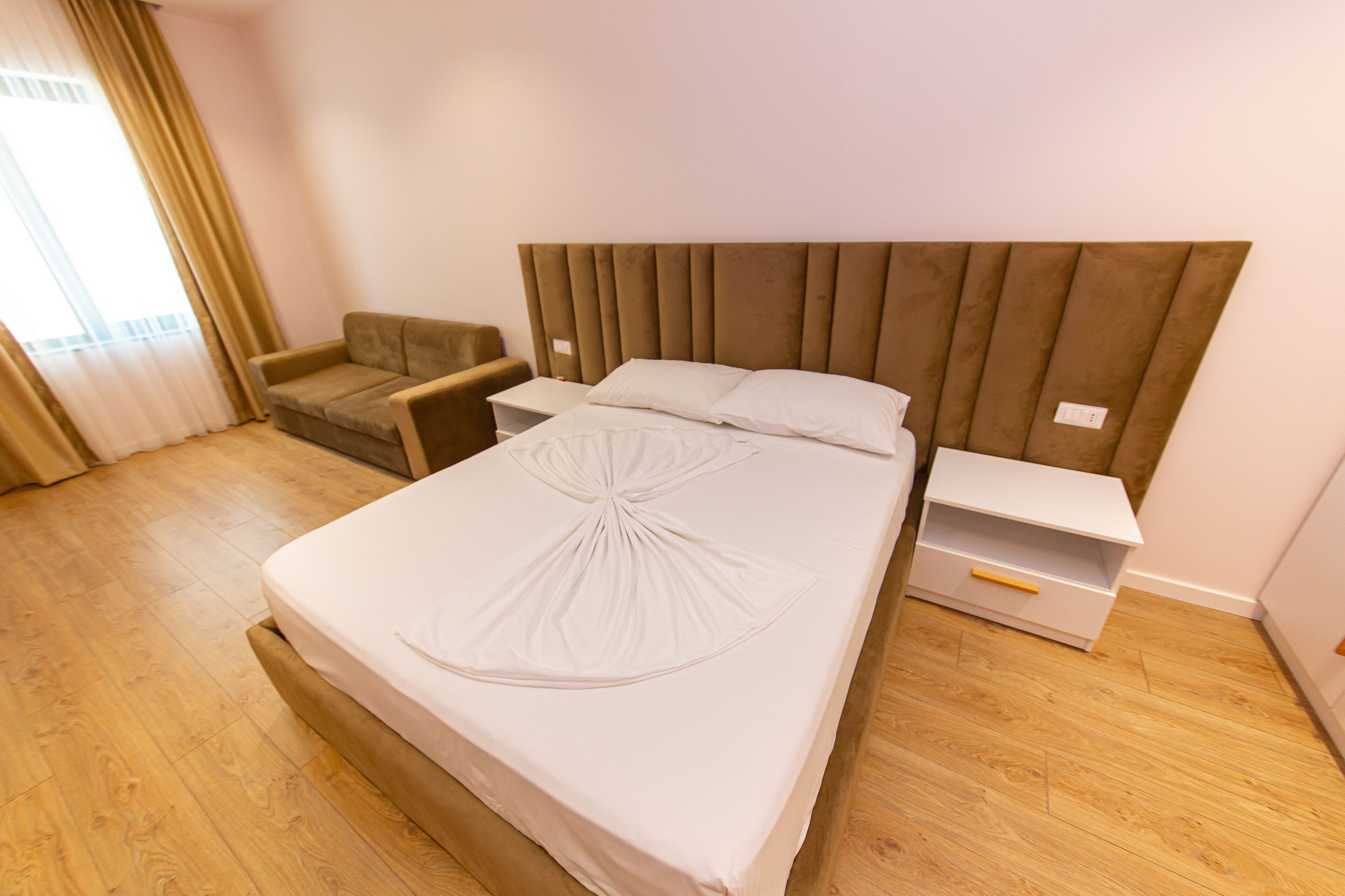 A neatly made bed with a headboard, a bedside table, a chair, and a nightstand.