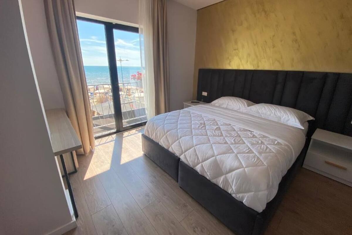 A bedroom with a large bed, a view of the sea, and a balcony.