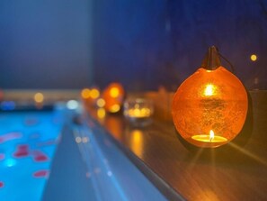 A row of spherical candle-like lights on a bar counter with a pool in the background.