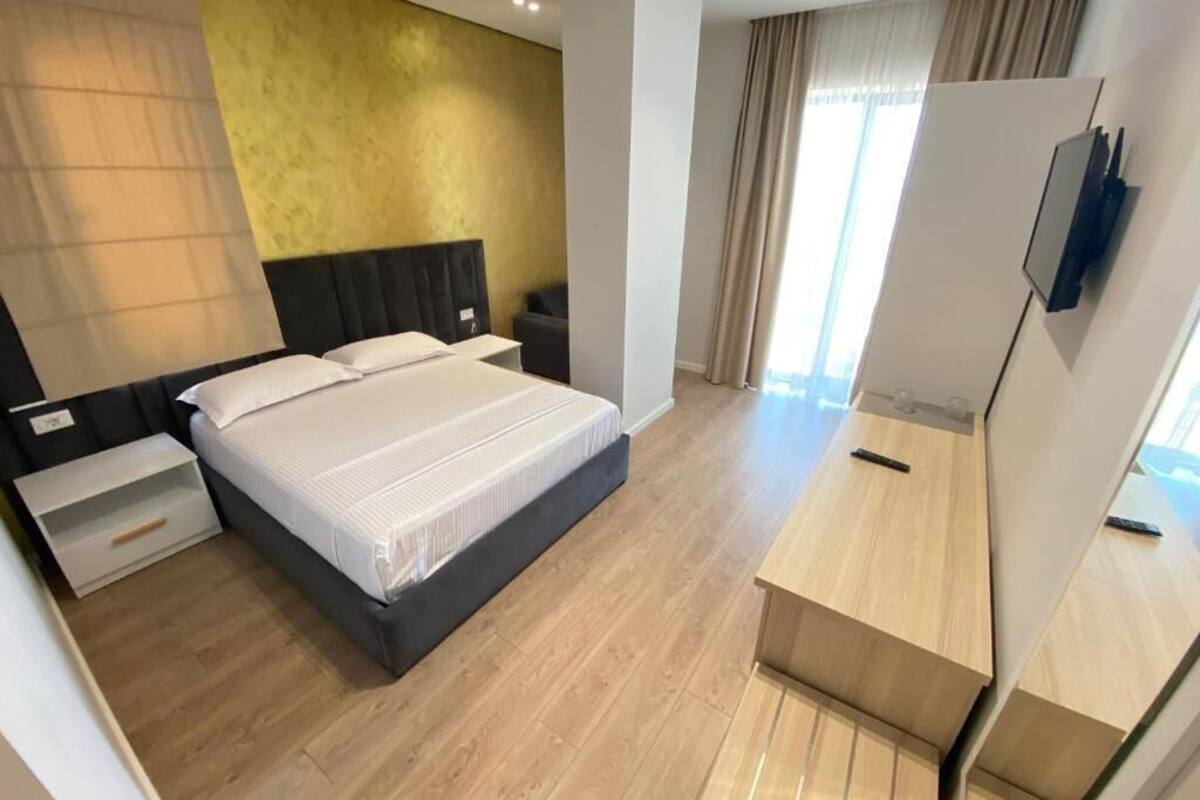 A modern hotel room with a large bed, a desk, and a TV mounted on the wall.