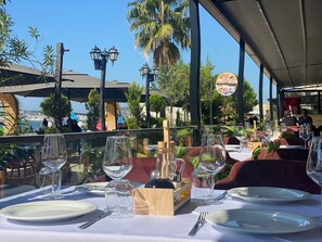 An outdoor dining area with tables set for two, overlooking a scenic view.