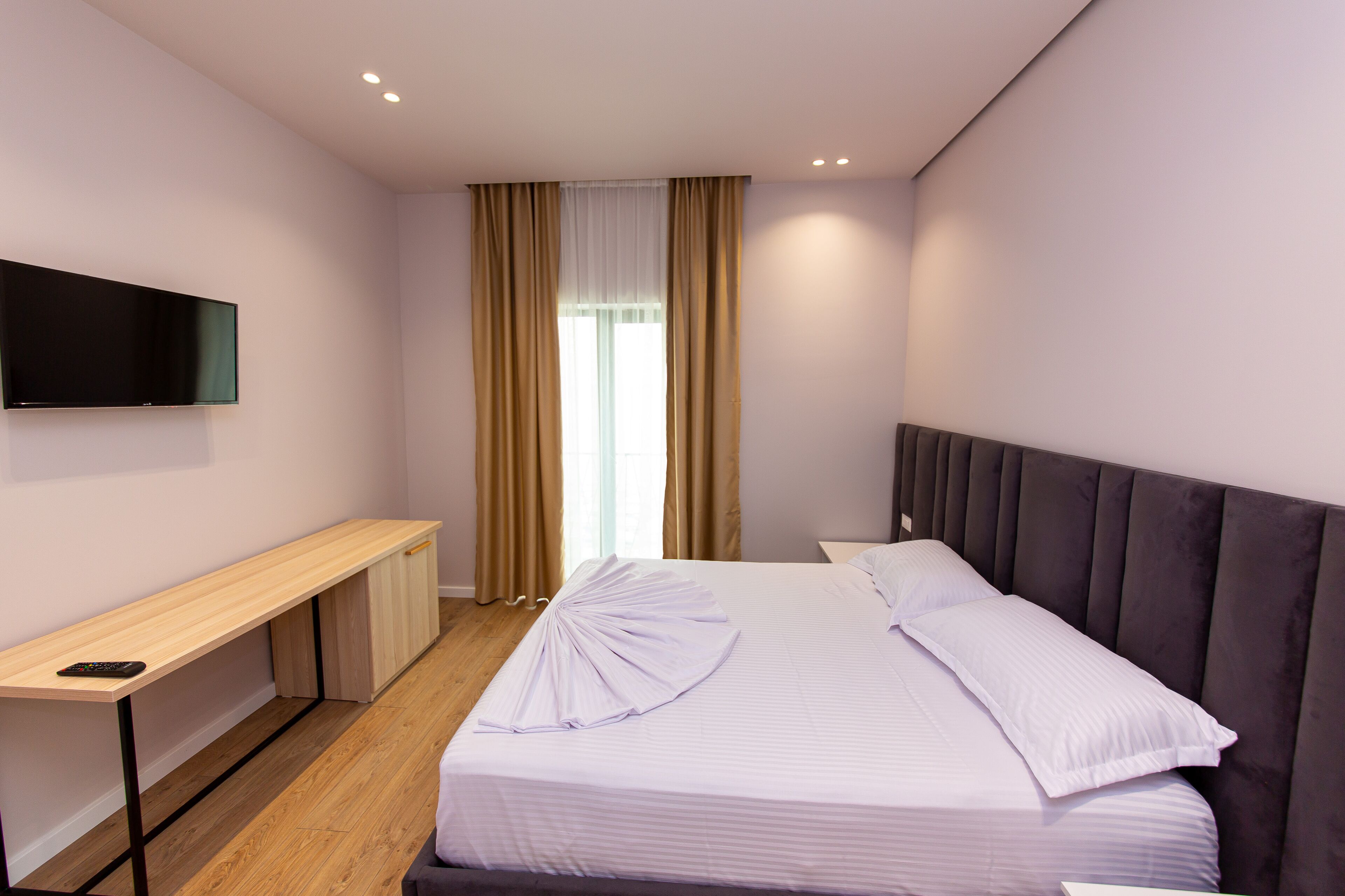 A modern hotel room with a bed, a desk, and a TV.