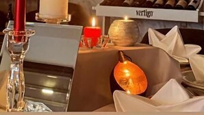 A dining table with candles, a wine rack, and a fireplace. - Hotel Alion (Durrës)