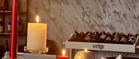 A dining table with candles, a wine rack, and a fireplace.