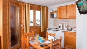 A compact kitchen with wooden cabinets, a microwave, a coffee maker, and a small dining area with a table and chairs.