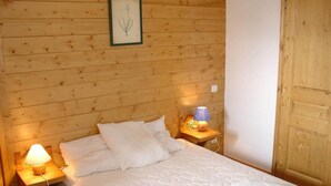 A wooden-paneled room with a bed, two bedside tables with lamps, and a door.