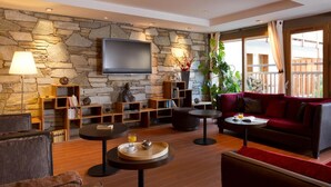 Un salon moderne avec un mur en pierre, un téléviseur à écran plat, un canapé rouge et une table basse.