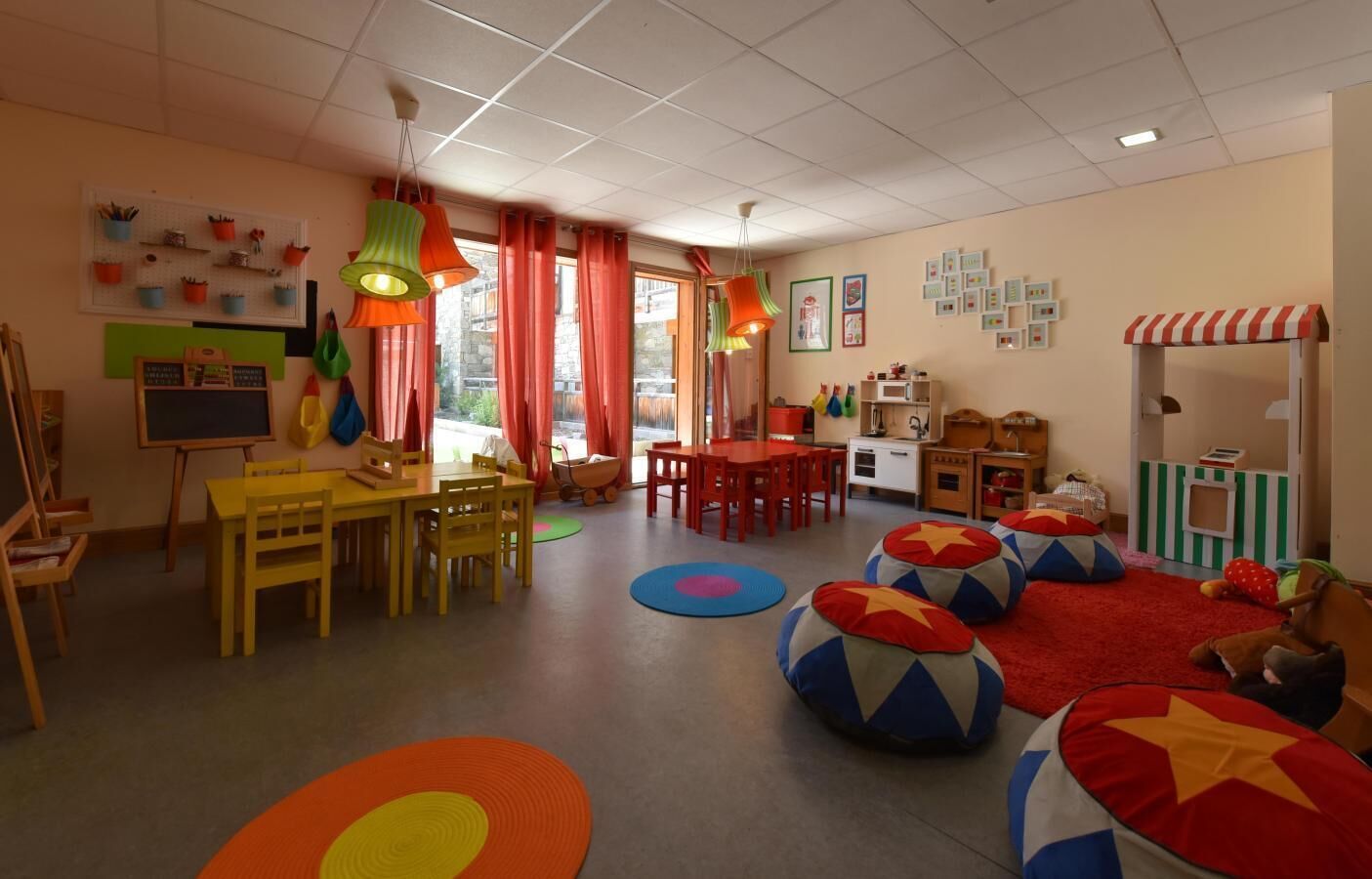A classroom with a chalkboard, tables, chairs, colorful bean bags, and educational toys.
