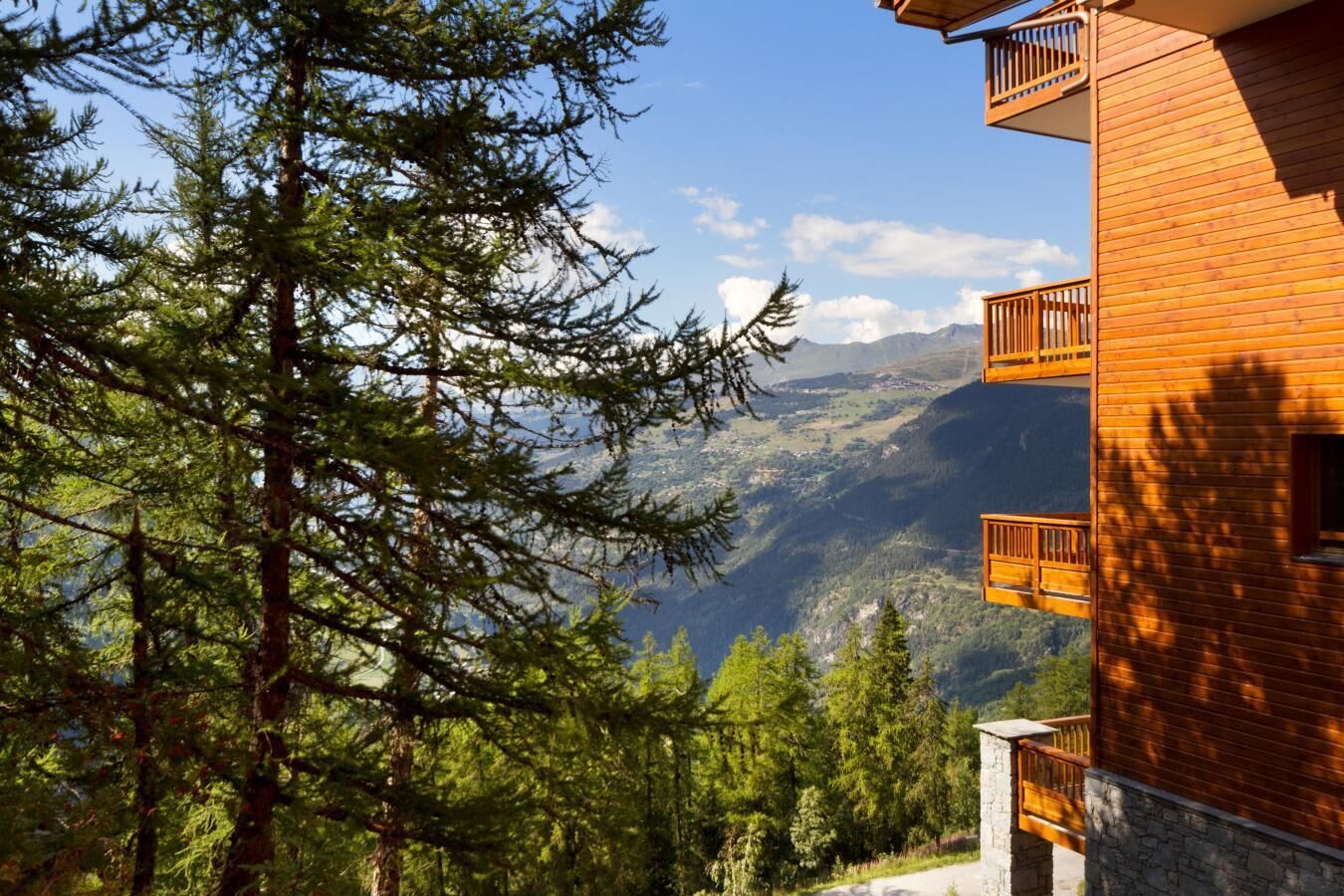 Ein Holzgebäude mit Balkonen mit Blick auf eine gebirgige Landschaft.