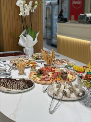 Une table de buffet proposant une variété d’aliments, notamment des fromages, des viandes et des fruits.