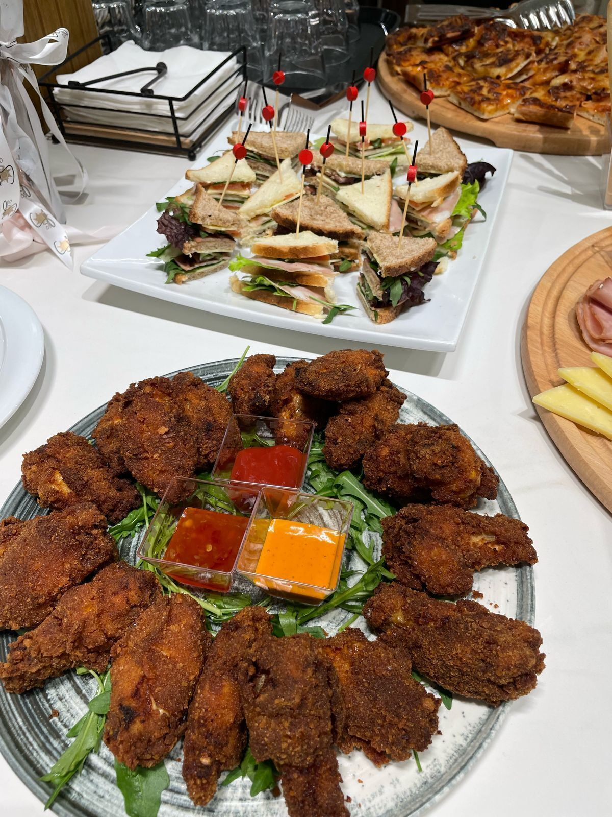 A buffet table with various dishes including sandwiches, fried chicken, and pizza.