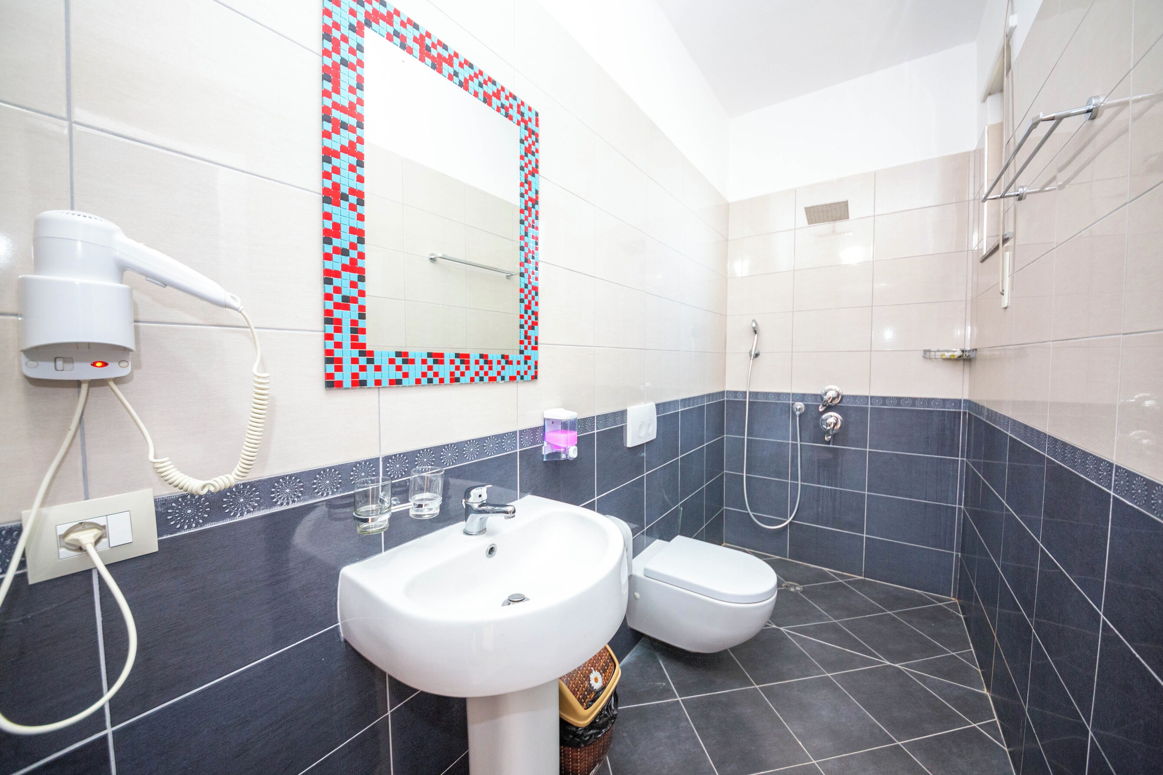 A modern bathroom with a white sink, a toilet, and a shower.
