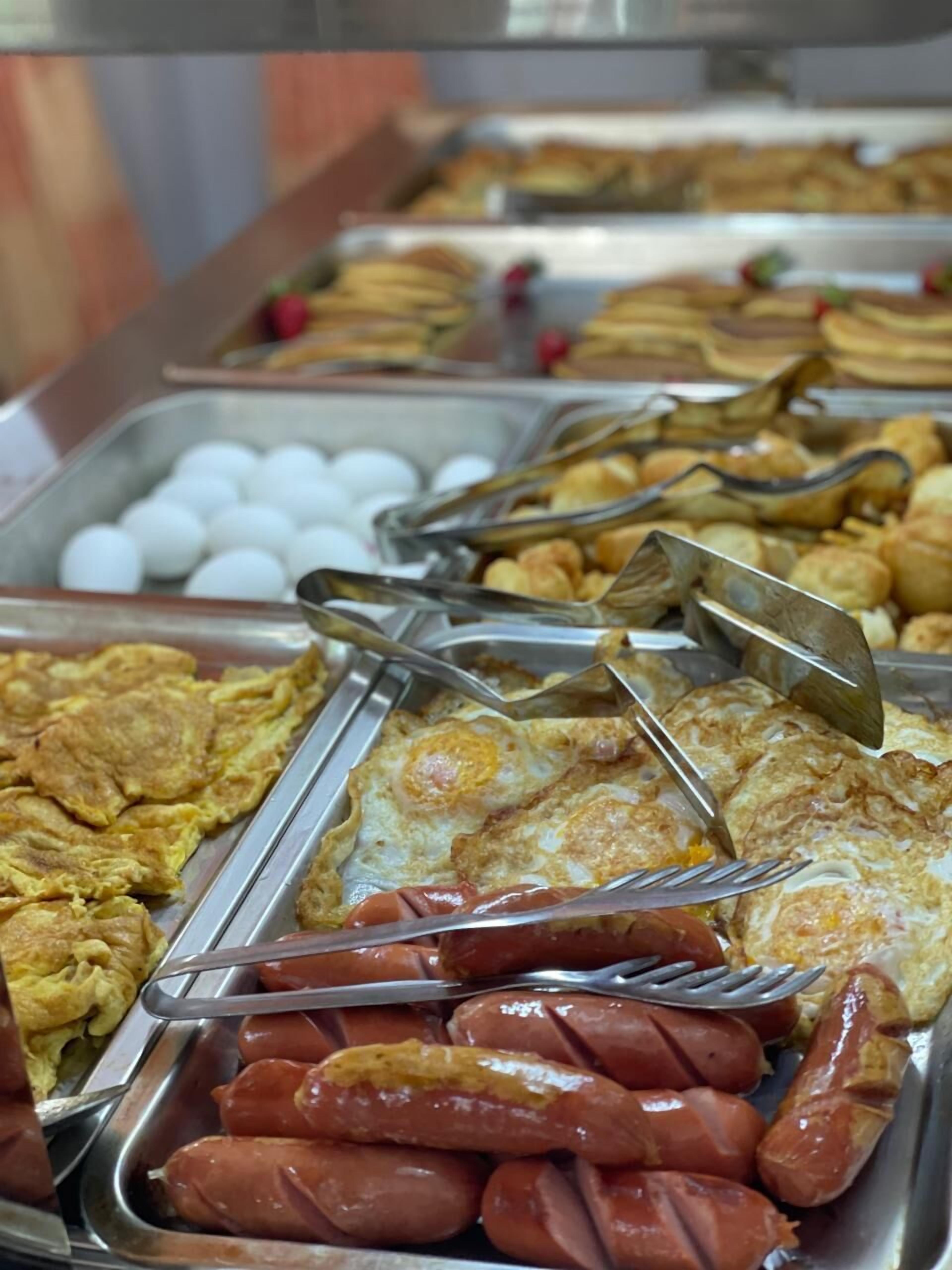 A buffet with various food items including eggs, sausages, and fried foods.