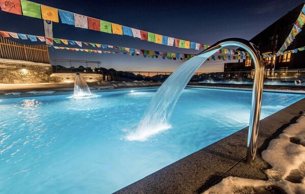 A pool with a water feature and colorful flags.