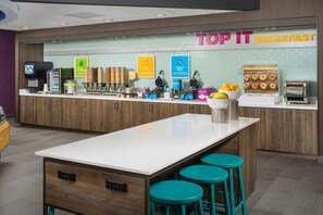 Un espace réservé au petit-déjeuner, avec un comptoir où sont exposés divers aliments et une pancarte indiquant : « PETIT-DÉJEUNER À VOLONTÉ ».