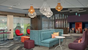 Un espace de détente moderne avec un canapé turquoise, des fauteuils rouges et violets, et diverses tables.