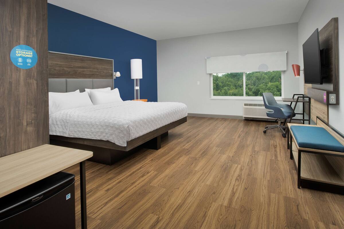 Une chambre d’hôtel moderne équipée d’un lit, d’un bureau, d’une chaise et d’une télévision.
