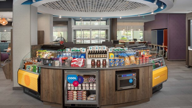 Un distributeur automatique proposant une variété d’aliments et de boissons, notamment des produits réfrigérés et une machine à café.
