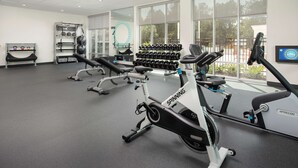 Une salle de sport équipée de vélos d’appartement, d’haltères et d’appareils d’exercice.