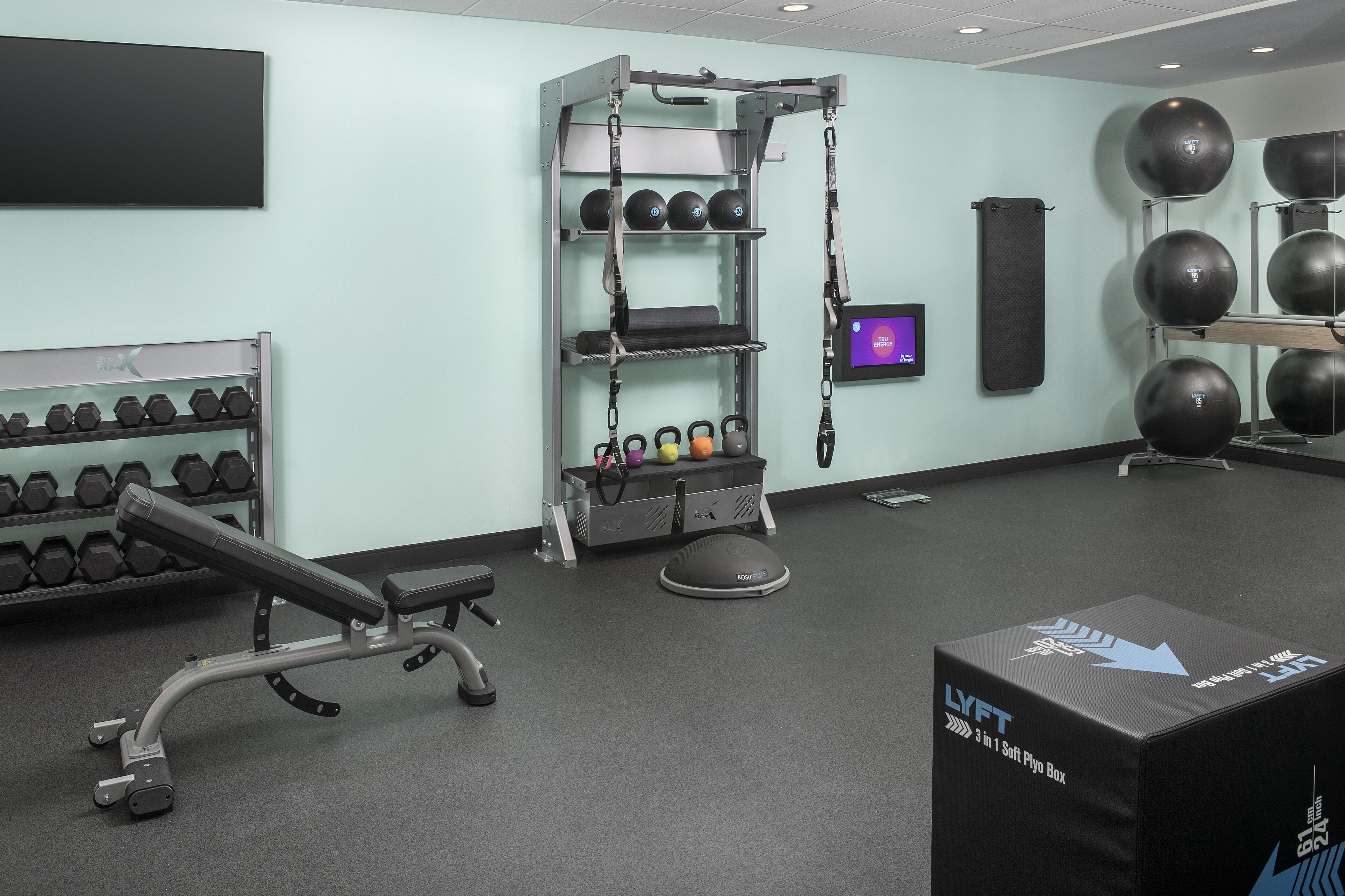 A gym with weightlifting equipment, exercise balls, and a bench.