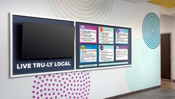 Una pared con una pantalla grande que muestra 'LIVE TRU-LY LOCAL' y varias atracciones locales.