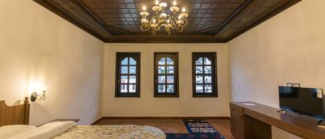 Un dormitorio con cama, escritorio, televisor y candelabro.