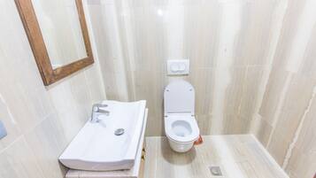 Un baño pequeño con lavamanos blanco, inodoro y espejo.