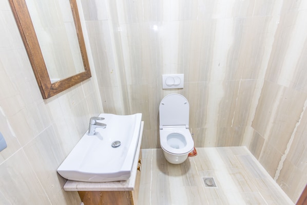 Un baño pequeño con lavamanos blanco, inodoro y espejo.