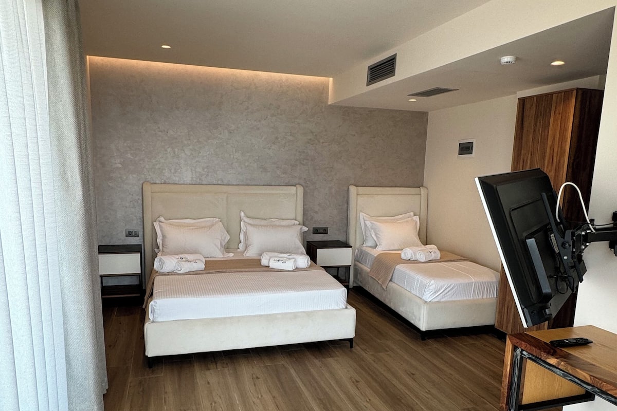 Habitación triple Deluxe, balcón, vistas al mar | Minibar, caja fuerte, escritorio y cortinas opacas