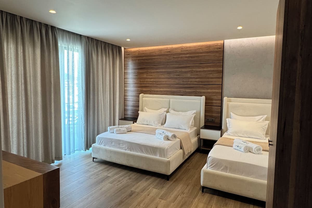 Habitación triple Deluxe, balcón, vistas parciales al mar | Minibar, caja fuerte, escritorio y cortinas opacas