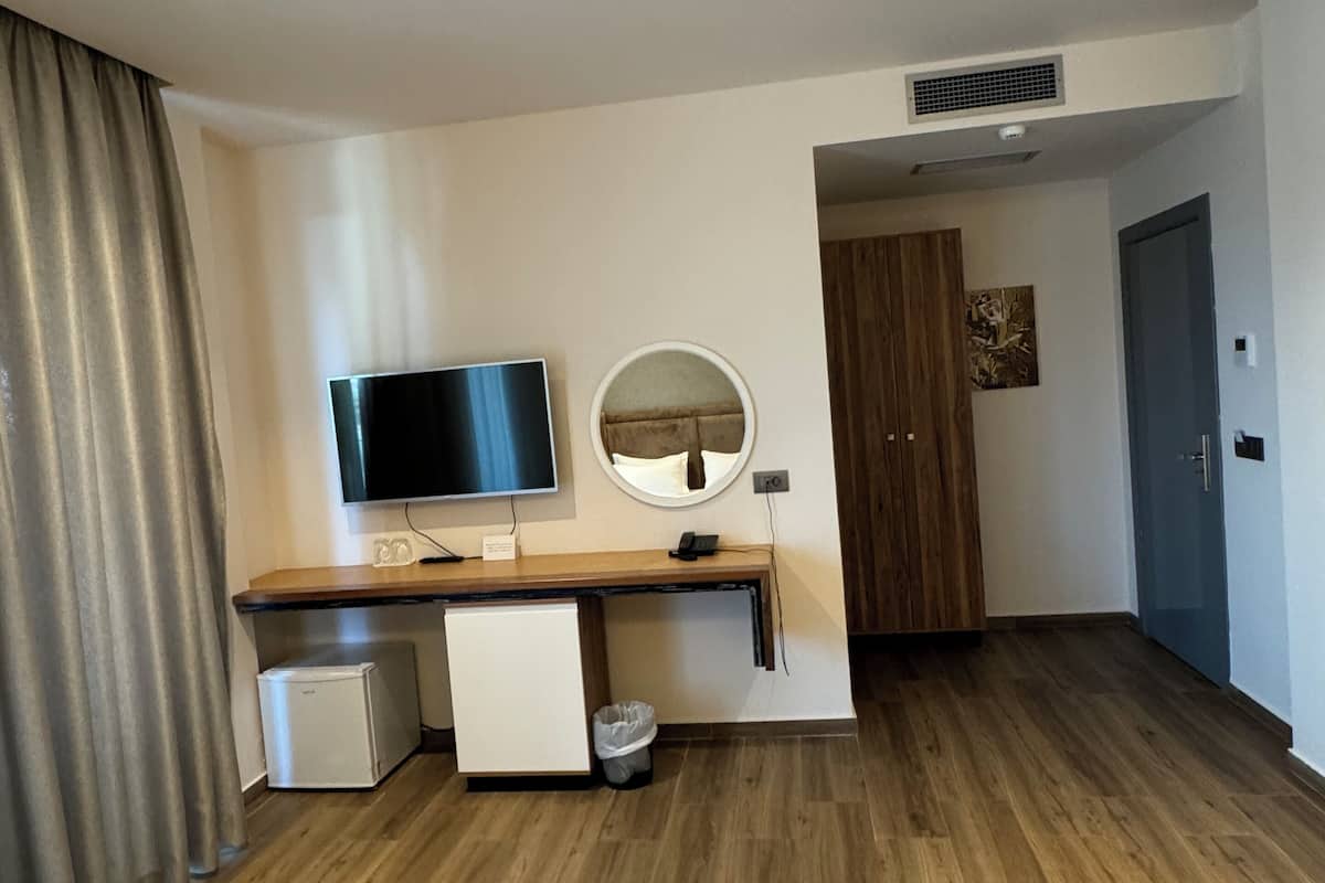 Habitación triple Deluxe, balcón, planta baja | Minibar, caja fuerte, escritorio y cortinas opacas