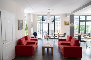 A modern reception area with red sofas, a wooden coffee table, and a chandelier.