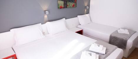 Una habitación de hotel moderna con una cama grande, una cama más pequeña y una zona de estar.