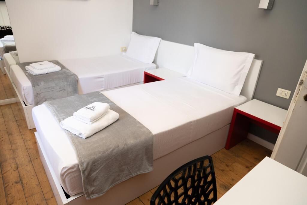 A hotel room with two single beds, a desk, and a chair.