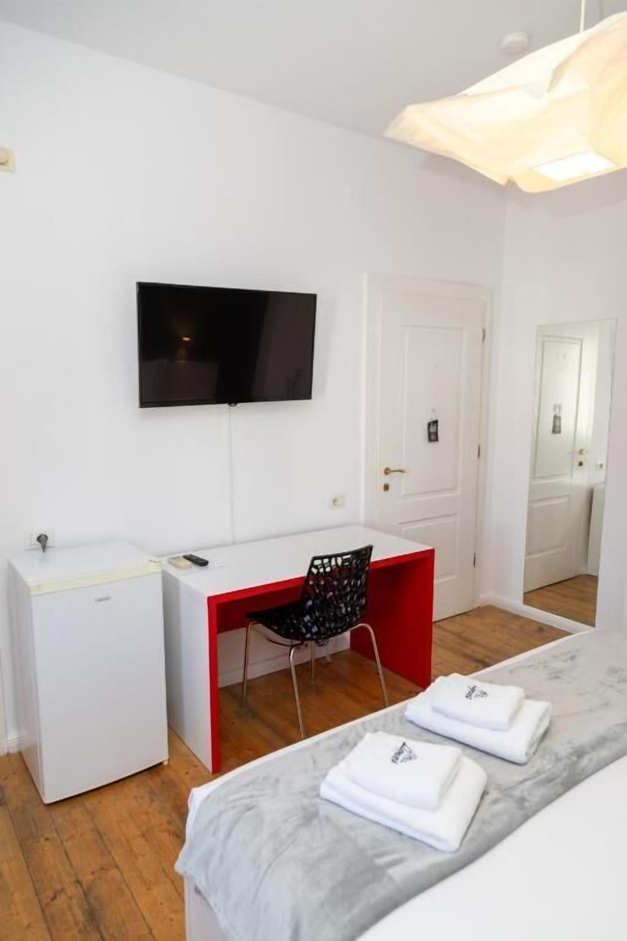 A room with a bed, a desk, a chair, a TV, and a wardrobe.