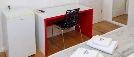 A room with a bed, a desk, a chair, a TV, and a wardrobe.